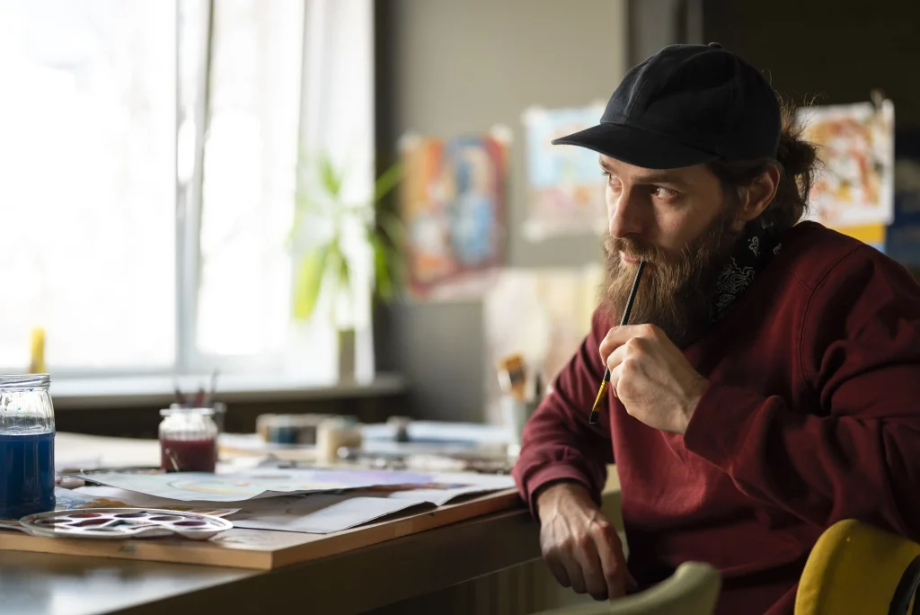 Bearded man painting at a desk 