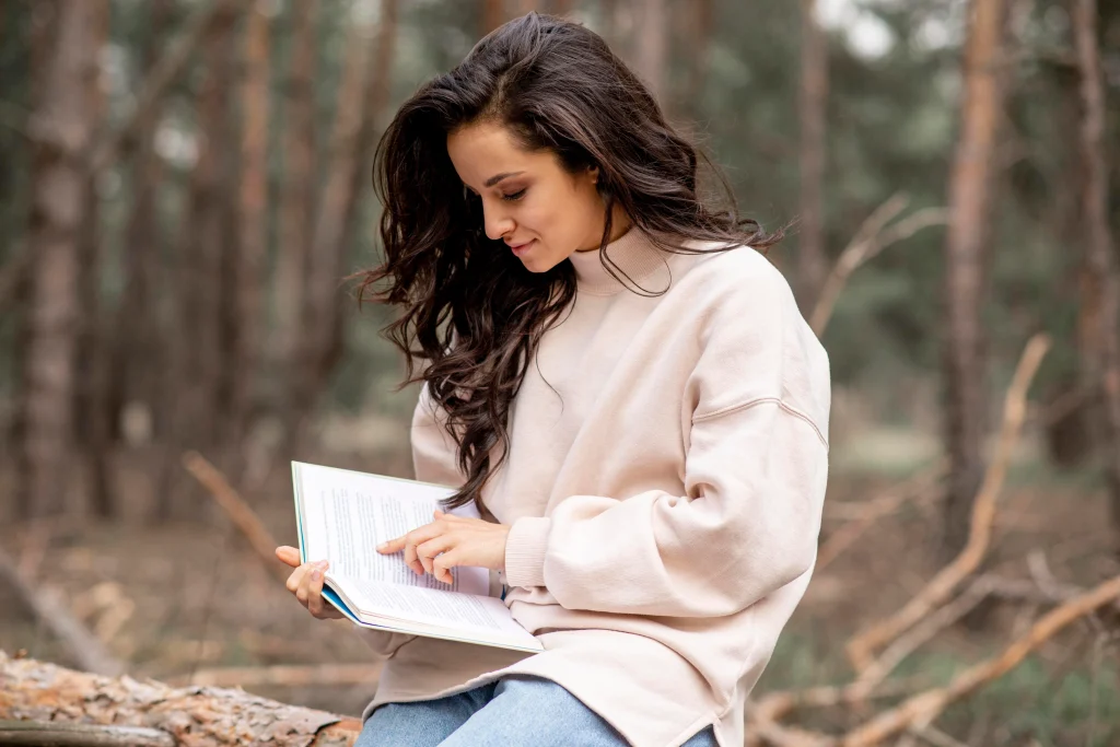 woman reading a book outdoors in a forest