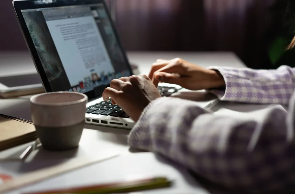 Freelance writer working on laptop with coffee on desk